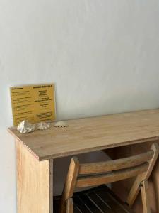 a wooden table with a sign and a wooden chair at Ayu Homestay in San Isidro