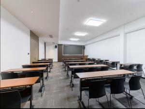 an empty classroom with tables and chairs and a screen at Ibis Styles Nantong North High-tech Zone in Nantong