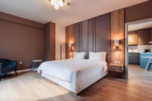 a bedroom with a large white bed and a kitchen at Syndicate Lodging Aparthotel in Cluj-Napoca