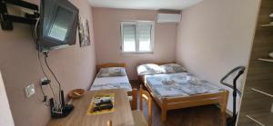 a small room with two beds and a television at Apartments Bellavista in Luštica