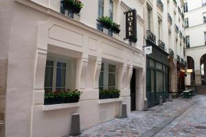un bâtiment blanc avec des plantes en pot dans une rue dans l'établissement Hôtel le Clos de Notre Dame, à Paris