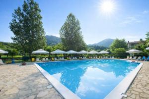 a large swimming pool with chairs and umbrellas at Agriani Hotel - Xanthi Pool & Mountain Views in Xanthi