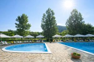 a pool at a resort with chairs and umbrellas at Agriani Hotel - Xanthi Pool & Mountain Views in Xanthi