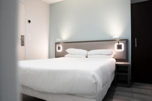 a bedroom with a large bed with white sheets and pillows at Aero Hotel in Issy-les-Moulineaux