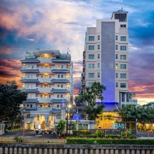 a tall white building next to two tall buildings at 1O1 URBAN Jakarta Thamrin in Jakarta