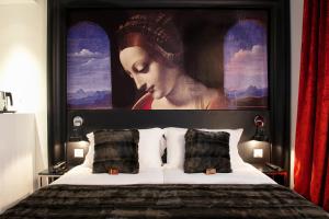 una cama con una gran pintura de una mujer en Hôtel le Clos de Notre Dame, en París