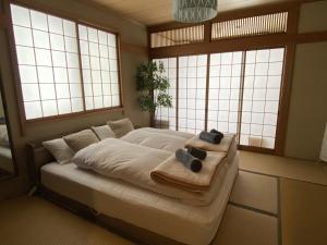 a bedroom with a bed with towels and windows at Seifuso At Myoko in Myoko