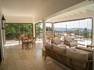 a living room with a couch and tables and windows at Oniro Guest House in Bedfordview