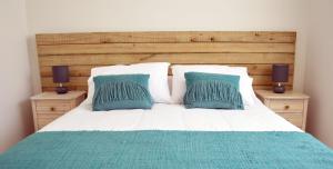 1 cama con 2 almohadas azules y 2 mesitas de noche en Apart Hotel Endurance en Punta Arenas