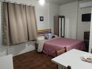 a small room with two beds and a table at Cabano rosa sul in Garopaba