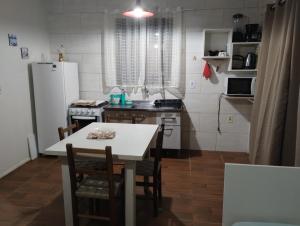 a kitchen with a table and chairs and a refrigerator at Cabano rosa sul in Garopaba
