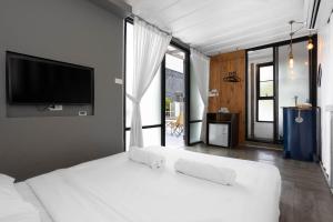 a bedroom with a white bed with a flat screen tv at serene hotel in Chiang Mai