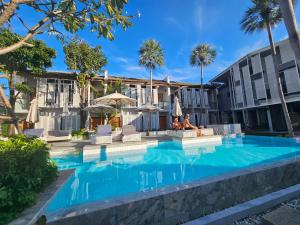 a swimming pool in front of a building with palm trees at Treevana Club Chiangmai in Chiang Mai