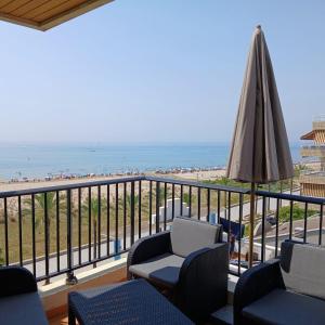 a balcony with chairs and an umbrella and the beach at Mar y Sol in Calafell