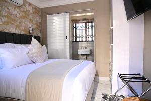 a bedroom with a large white bed and a bathroom at His Grace Eagles Guesthouse in Bloemfontein +23 photos
