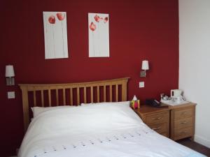 1 dormitorio con cama blanca y pared roja en Mountbatten Hotel en Plymouth