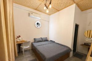 a small bedroom with a bed and a table at Tròn Homestay Vĩnh Hy in Vĩnh Hy