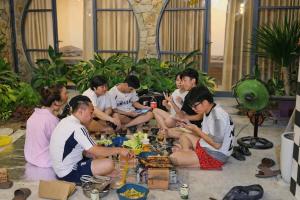 a group of people sitting on the floor playing chess at Tròn Homestay Vĩnh Hy in Vĩnh Hy