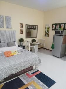 a bedroom with a bed and a table and a refrigerator at Precious Ruby's Apartment in Manila
