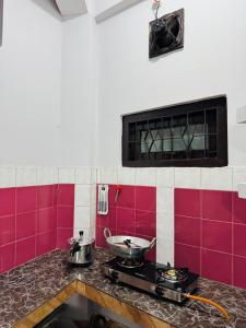 a kitchen with a stove and red and white tiles at Nibha Homestay Near Guwahati Railway station 2BHK in Guwahati +2 photos