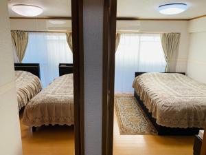 a reflection of a bedroom with two beds and a mirror at HOTEL k&m in Tokyo