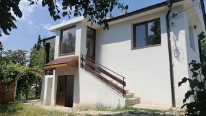 a white house with a staircase on the side of it at къща за гости При Приятели in Nesebar