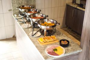 a buffet with several bowls of food on a counter at His Grace Eagles Guesthouse in Bloemfontein