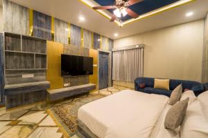a bedroom with a tv and a bed and a couch at Lumira Queensbury Villa in Udaipur
