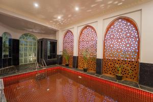 a swimming pool in a room with three arched windows at Lumira Queensbury Villa in Udaipur
