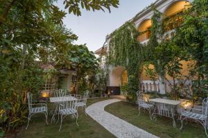 a patio with tables and chairs in front of a building at Lumira Queensbury Villa in Udaipur