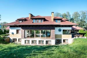 a house with a red roof on a green field at Villa Victoria in Rydzewo