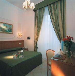ローマにあるホテル フィリアのベッドルーム1室(緑のベッド1台、テーブル、窓付)