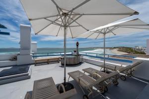 a balcony with two chairs and an umbrella at Seehuis Studios in Langebaan