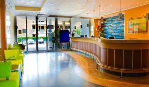 a lobby with a bar and some green chairs at Casa del Mar - Residence & Beach Resort in Roseto degli Abruzzi