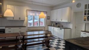 a kitchen with white cabinets and a wooden table at Kauppilan Matkailutalo in Ikaalinen