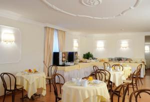 uma sala de jantar com mesas e cadeiras com toalha de mesa branca em Hotel Torino em Roma