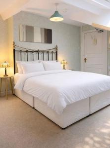 a large white bed in a bedroom with two lamps at The Manor House in Peel +25 photos