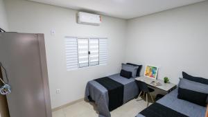a bedroom with a bed and a desk and a window at Jahu Center Casas Un 5 in Jaú