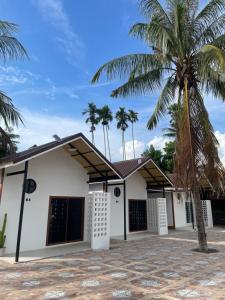 a house with a palm tree in front of it at โรงแรมสบายดีรีสอร์ท in Tha Bo