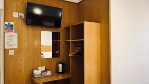 a room with a tv and a wooden wall at West Cromwell Hotel in London