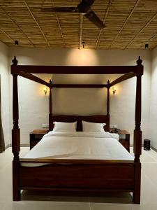 a bedroom with a large wooden bed with white sheets at Jalsa Jawai Resort in Bīsalpur
