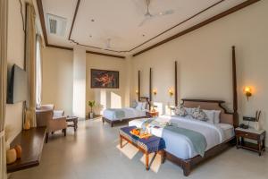 a bedroom with two beds and a living room at Luxuria Varanasi By Moustache in Varanasi