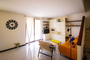 a living room with a couch and a clock on the wall at La casa di a-mici in Maccagno Superiore