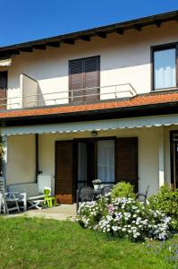 a house with a patio with chairs and flowers at La casa di a-mici in Maccagno Superiore