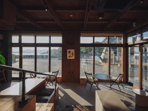 ein Zimmer mit Stühlen, einem Tisch und Fenstern in der Unterkunft SOIL Setoda in Onomichi