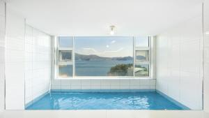 a swimming pool with a window in a bathroom at Geoje Badageurigo Pension in Geoje