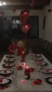 a table with red candles and a teddy bear on a table with balloons at Алтъна Калофер in Kalofer
