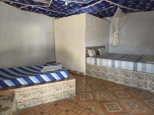 a room with two beds in a room with a ceiling at Finfoot Lodge in Lamin Koto