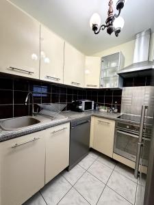 a kitchen with white cabinets and stainless steel appliances at T2 Evry Centre - Proche de Orly et Paris in Courcouronnes