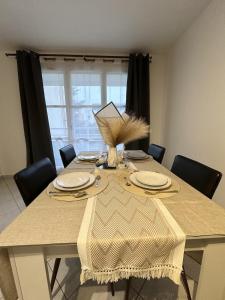a dining room table with plates and a vase on it at T2 Evry Centre - Proche de Orly et Paris in Courcouronnes +26 photos
